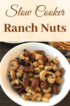 a white bowl filled with nuts on top of a wooden table next to a sign that says slow cooker ranch nuts