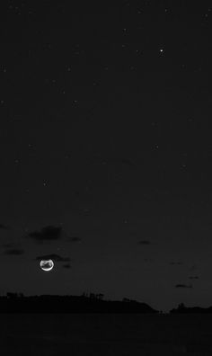 the moon and venus are seen in the night sky with stars above it, as well as some clouds