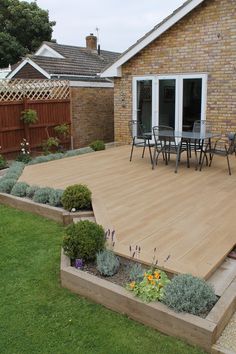 an outdoor patio with wooden decking and landscaping