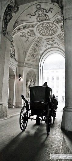 an old horse drawn carriage is parked in the middle of a building with arches and pillars