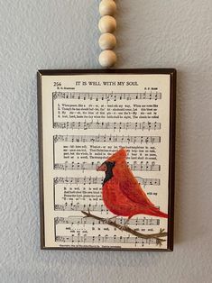 a red bird sitting on top of a sheet of music