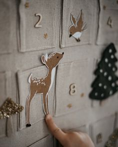 a hand is pointing at the numbers on a wall with deer and christmas tree magnets