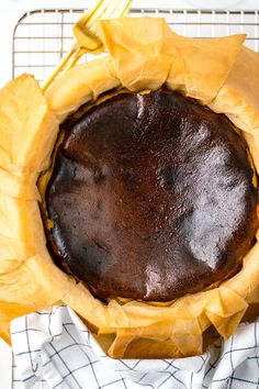 a chocolate cake sitting on top of a cooling rack with yellow paper wrapped around it