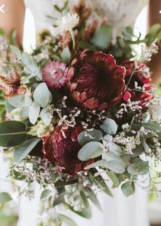 a bride holding a bouquet of flowers and greenery