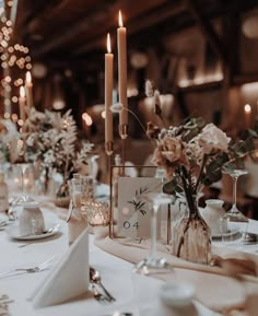 the table is set with candles and flowers in vases, plates and napkins