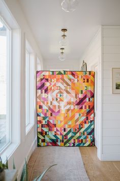 a colorful quilt hanging on the wall in a hallway