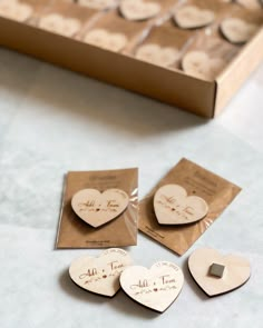 four wooden hearts with names on them sitting in front of a cardboard box filled with cards