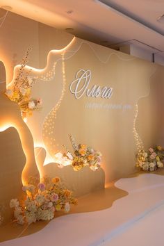 an elegant display with flowers and lights on the wall in front of a sign that says oscara