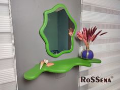 a green shelf with a mirror and vase on it