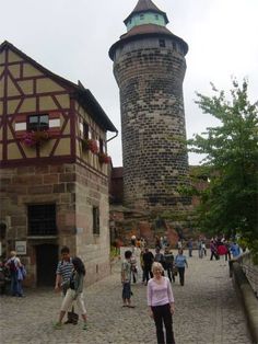 people are walking around in front of an old building with a tower on the other side