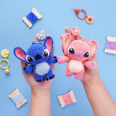 two small crocheted stuffed animals are held in their hands, one is pink and the other is blue