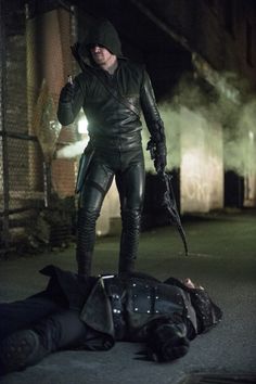 a man in black leather clothes standing next to a dead person on the ground at night