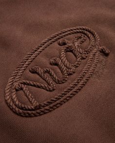 a close up view of the logo on a brown jacket with braids around it