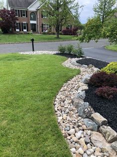 there is a rock garden in front of the house with grass and rocks around it