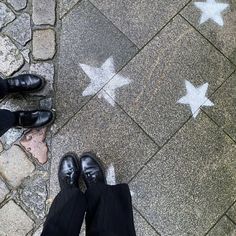 two people standing in front of a star on the ground with their feet up and one person wearing black shoes