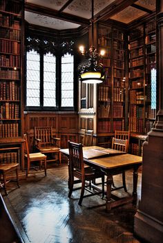 an old library with many bookshelves and wooden tables in the center is full of chairs