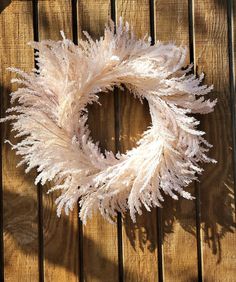 a white feather wreath hanging on a wooden fence