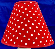 a red and white polka dot lamp shade on a blue background with room for text