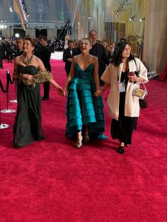 two women in dresses walking down the red carpet at an oscars event with one woman holding her hand