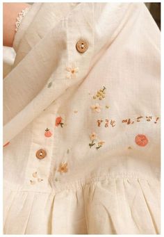 an embroidered dress with buttons and flowers on it