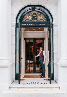 a man standing in front of a hotel entrance with his hand on the glass door