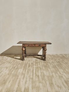 a wooden table sitting on top of a hard wood floor next to a white wall