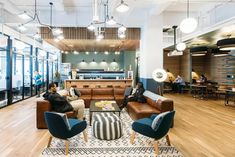 two people sitting on couches in a large room with wood floors and high ceilings