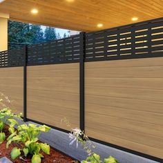 a wooden fence next to a house with plants growing on the ground in front of it