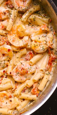 a pan filled with pasta and shrimp covered in seasoning sprinkled on top