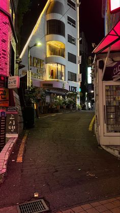 an empty street at night with buildings lit up