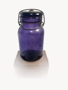 a purple glass jar sitting on top of a wooden table