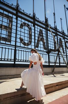 a woman in a white dress is standing on the steps near a sign that reads chicago