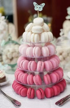 a stack of pink and white macaroons with a butterfly on top