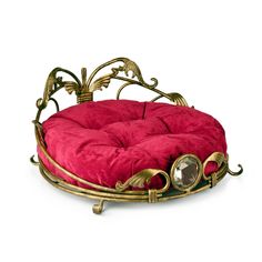 a red round dog bed with gold trimmings on the sides and a metal frame around it