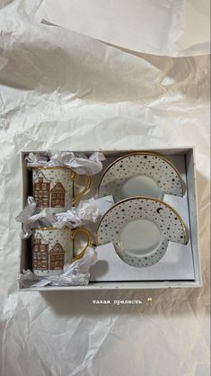 a boxed set of four coffee cups and saucers in a box with white paper