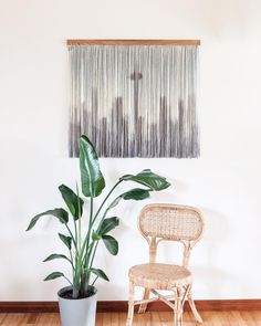 a chair next to a potted plant in front of a wall hanging on the wall