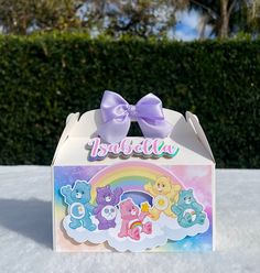 an open box with some teddy bears on it and a rainbow in the sky inside