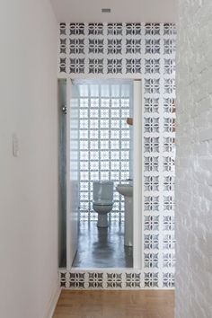 a white toilet sitting inside of a bathroom next to a wall covered in geometric tiles