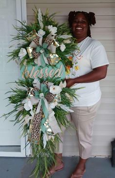 a woman standing next to a door holding a wreath with the words raised on it