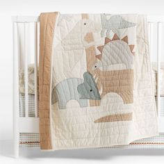 a baby crib with an elephant and giraffe quilt on it