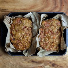 two hamburger patties sitting on top of each other in a black container with brown paper