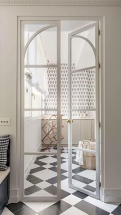 an entryway with black and white checkered flooring, arched glass doors leading into the dining room