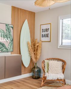 a surfboard is hanging on the wall next to a wicker chair and vase