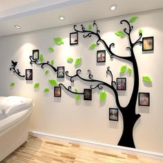 a tree with many frames on it in front of a white wall and wooden floor