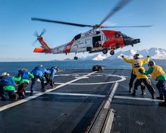 a helicopter is taking off from an aircraft carrier on the water with people around it