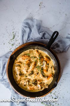 a skillet filled with food sitting on top of a table next to a napkin