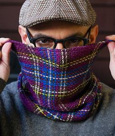 a man wearing a hat and scarf with glasses on his face is covering his face