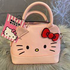 a hello kitty purse with a red bow on the front and a pink bag tag attached to it