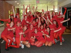 a group of women in red shirts posing for a photo with their arms up and hands in the air