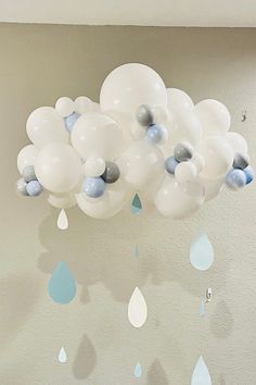 white and blue balloons are floating in the air on a ceiling with raindrops